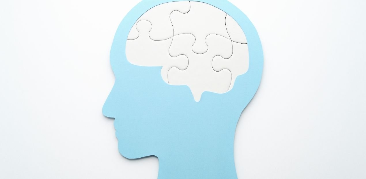 Silhueta de cabeça azul com cérebro em peças de quebra-cabeça, simbolizando como os sintomas do TOC Transtorno Obsessivo Compulsivo fragmentam pensamentos e ações.