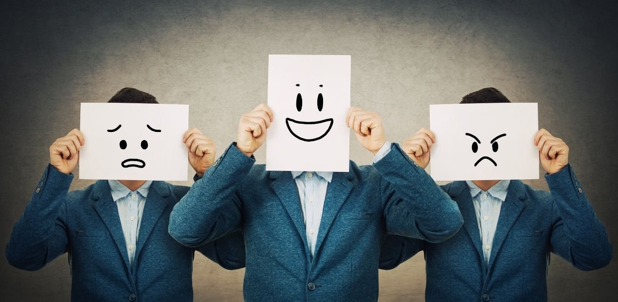 Homem bipolar no relacionamento ilustrado por três figuras idênticas vestindo terno azul, cada uma segurando uma folha com rosto desenhado — um triste, um feliz e um irritado — simbolizando as oscilações de humor típicas do transtorno bipolar.