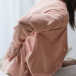 Pessoa sentada segurando a região lombar, ilustrando como o estresse causa dor no corpo