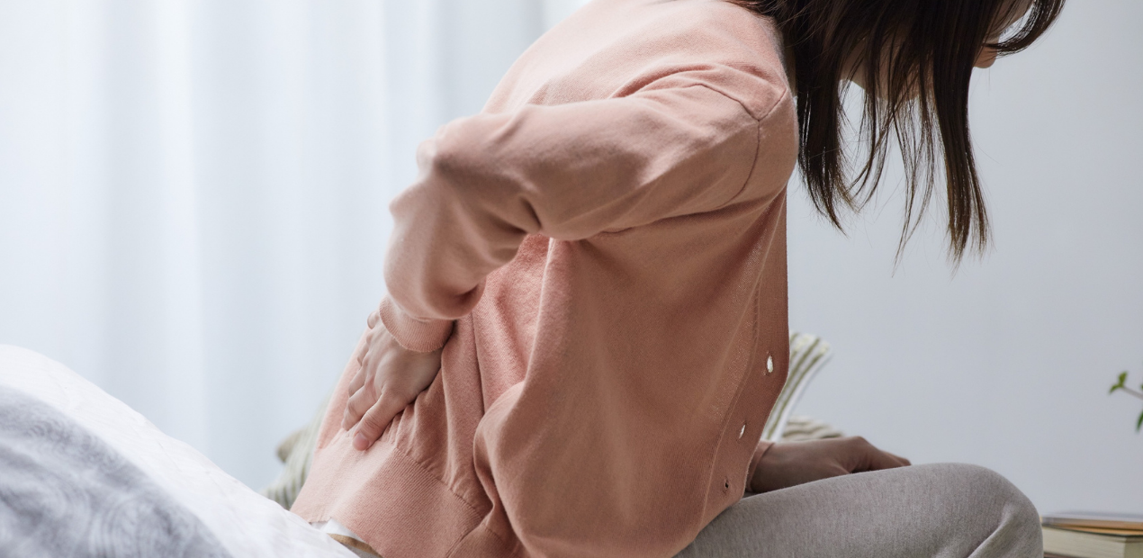 Pessoa sentada segurando a região lombar, ilustrando como o estresse causa dor no corpo