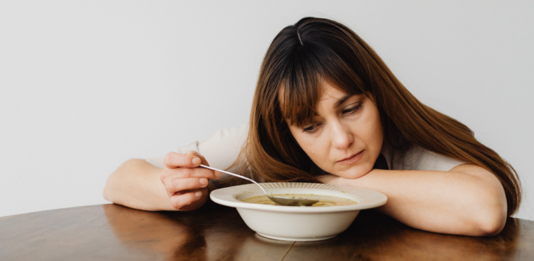 Pessoa em sofrimento emocional diante da comida, situação comum em quadros que exigem tratamento para compulsão alimentar