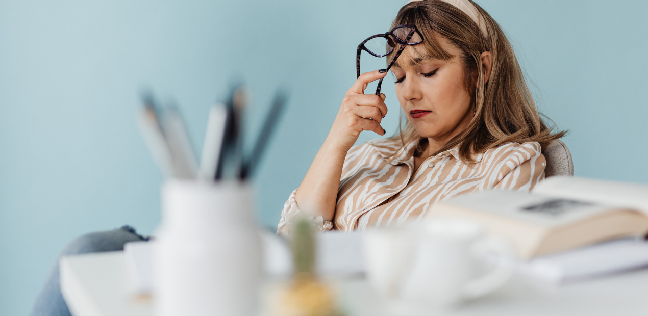 A sobrecarga do dia a dia pode refletir no corpo e na mente. A expressão de cansaço dessa mulher mostra como os sintomas do estresse emocional (1300) podem afetar a produtividade e o bem-estar.