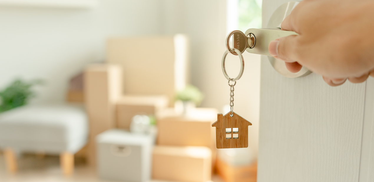 Chave na porta com chaveiro em formato de casa, representando a entrada em um novo lar e o impacto do ambiente na saúde mental