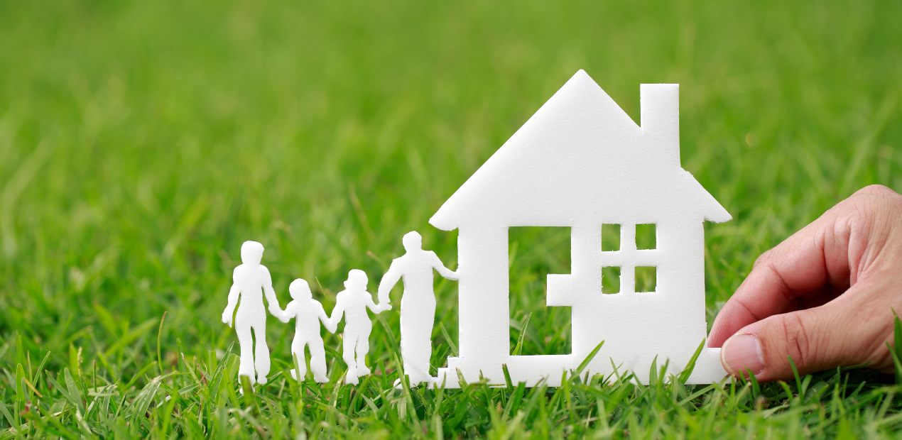 Silhuetas de família ao lado de uma casa sobre a grama, simbolizando a escolha do lar ideal e o impacto do ambiente na saúde mental
