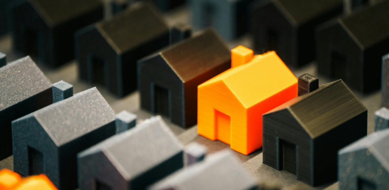 Casas em miniatura com uma residência em destaque, simbolizando a escolha consciente do ambiente e seu impacto na saúde mental