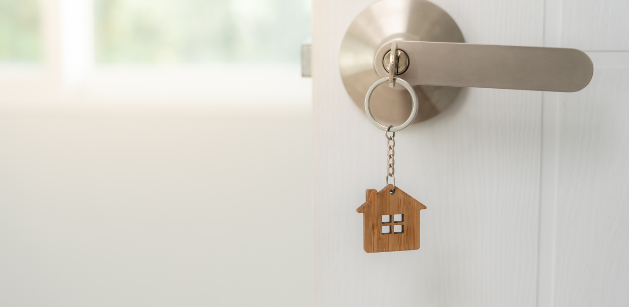Chaveiro em formato de casa pendurado na maçaneta simbolizando o lar como espaço de equilíbrio emocional e saúde mental