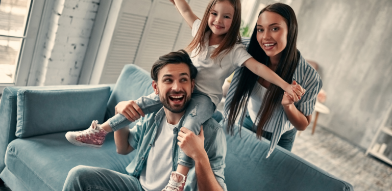Família reunida na sala de casa, sorrindo e interagindo, representando bem-estar emocional e convivência familiar em um ambiente acolhedor