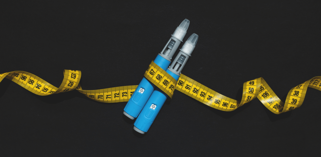 Duas canetas aplicadoras envolvidas por fita métrica amarela, em conteúdo sobre caneta emagrecedora efeitos colaterais