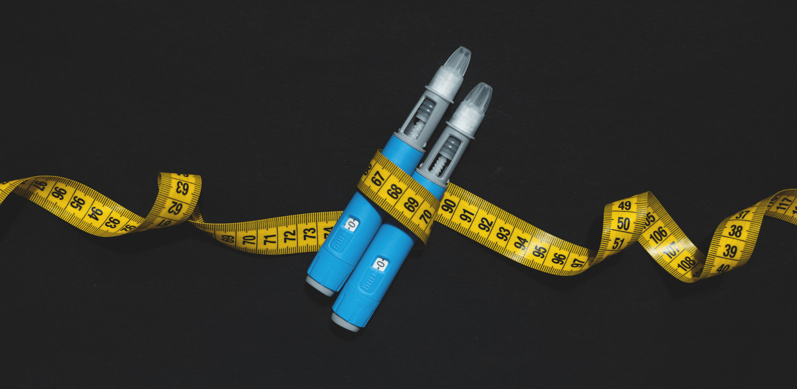 Duas canetas aplicadoras envolvidas por fita métrica amarela, em conteúdo sobre caneta emagrecedora efeitos colaterais