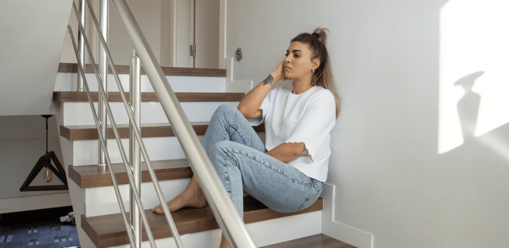 Mulher sentada na escada, representando medo de mudar de cidade