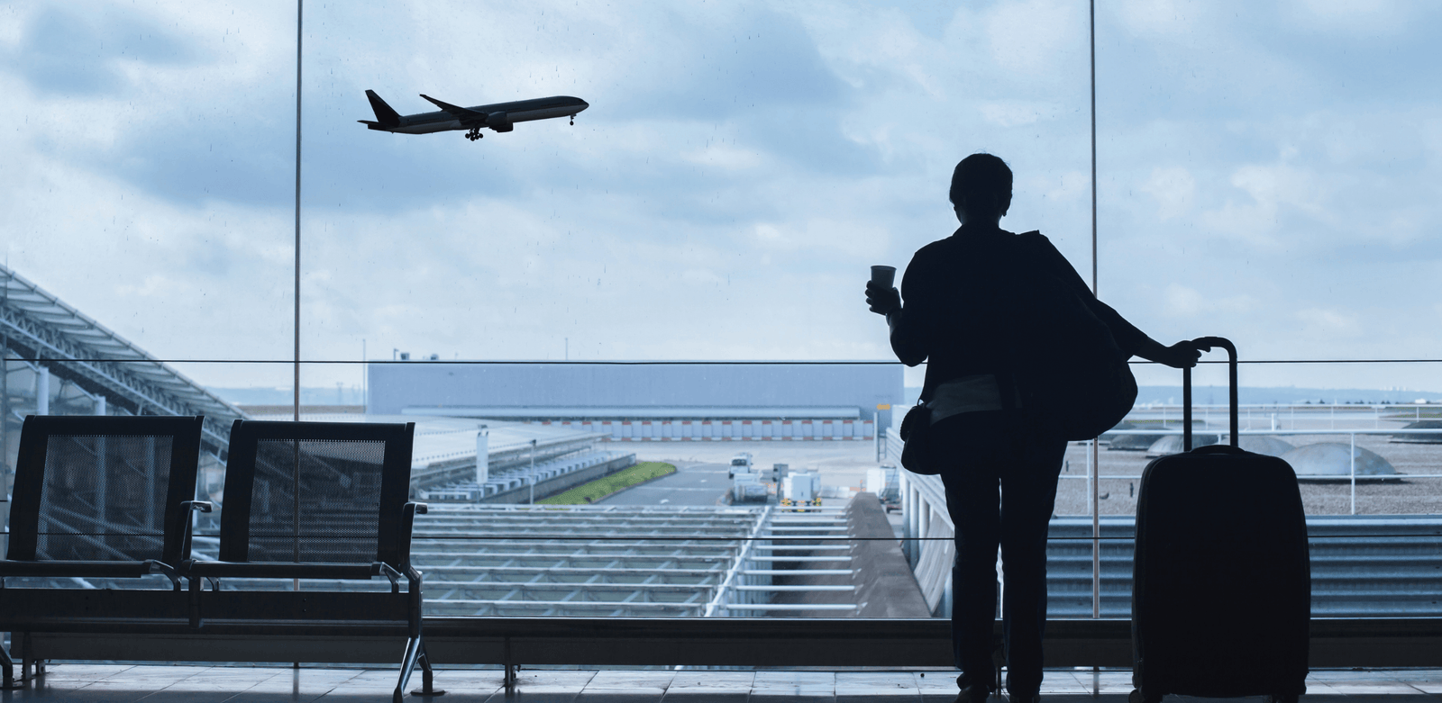Pessoa em silhueta no aeroporto, com mala ao lado e avião ao fundo, representando medo de mudar de cidade