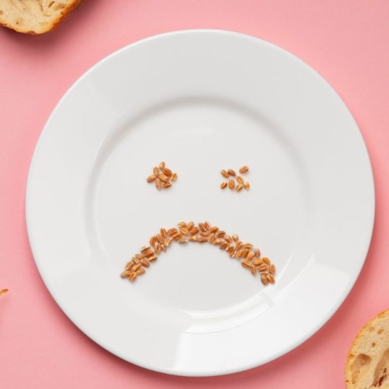 Prato branco com grãos formando um rosto triste, simbolizando a relação difícil com a comida e o transtorno alimentar