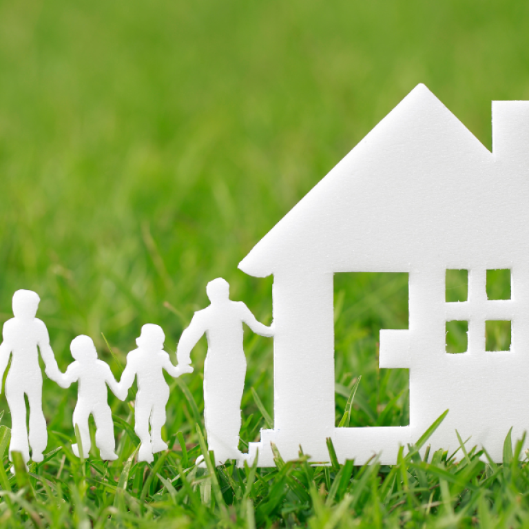 Silhuetas de família ao lado de uma casa sobre a grama, simbolizando a escolha do lar ideal e o impacto do ambiente na saúde mental