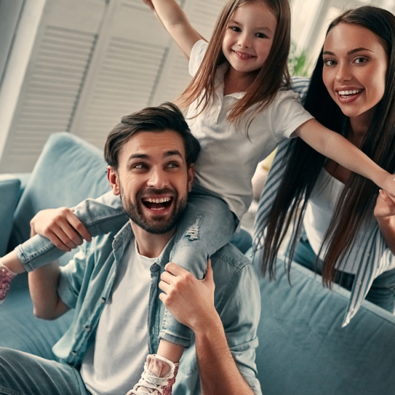 Família reunida na sala de casa, sorrindo e interagindo, representando bem-estar emocional e convivência familiar em um ambiente acolhedor