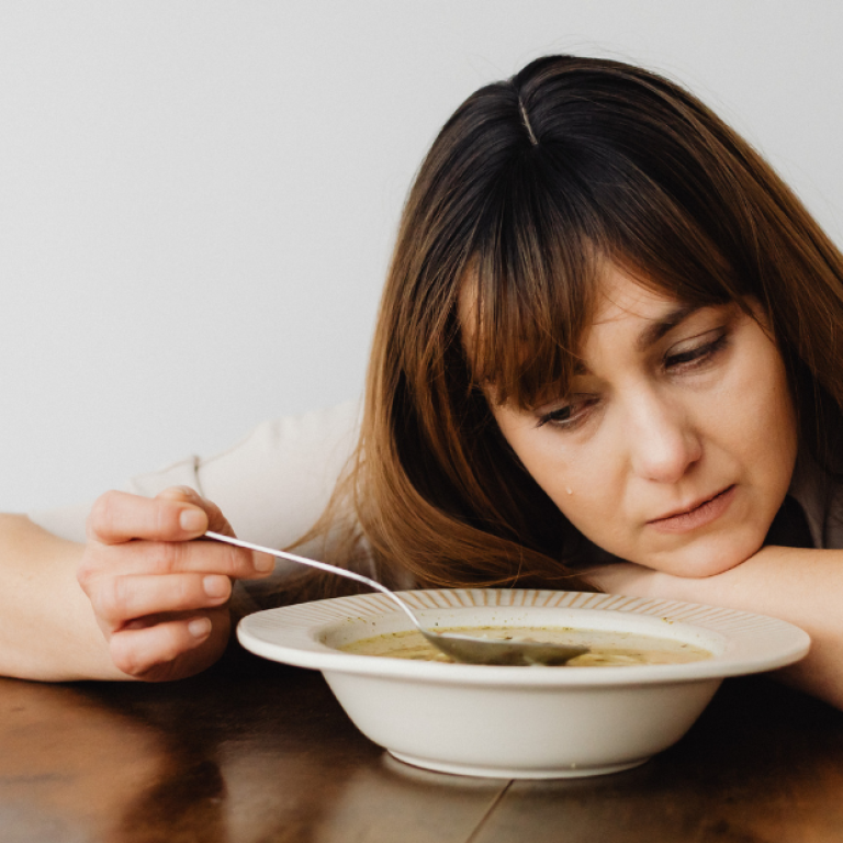 Pessoa em sofrimento emocional diante da comida, situação comum em quadros que exigem tratamento para compulsão alimentar