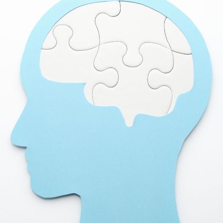 Silhueta de cabeça azul com cérebro em peças de quebra-cabeça, simbolizando como os sintomas do TOC Transtorno Obsessivo Compulsivo fragmentam pensamentos e ações.